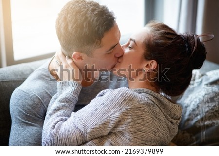 Passionate kisses on the couch. Shot of an affectionate young couple kissing on the sofa at home.