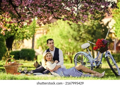 Passionate Love. Happy Couple In Love. Woman And Man Lying In Park And Enjoying Day Together. Valentines Day Picnic. Romantic Picnic In Park. Couple Date On Blanket Under Sakura Flowers. Camping