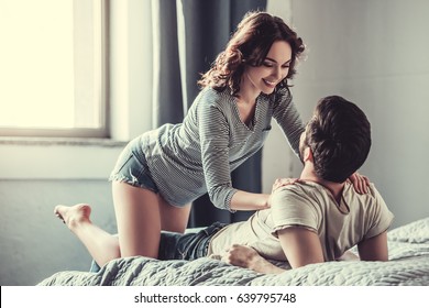 Passionate love. Happy young couple hugging and smiling while lying on the bed in a bedroom at home.