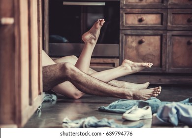 Passionate love. View of feet of a young couple that lying on the floor in the kitchen at home.