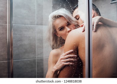 passionate man embracing and kissing beautiful woman in shower 