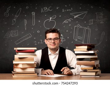 Ein leidenschaftlicher junger Lehrer, der an einem Schreibtisch sitzt, mit einem Stapel Bücher vor der Tafel, die voll von zurück zu den Schulartikeln Konzept gezogen.