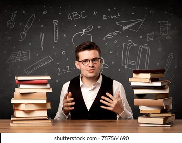 A passionate young teacher sitting at school desk with pile of books in front of blackboard drawn full of back to school items concept.
