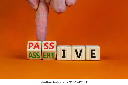 Passive or assertive symbol. Businessman turns wooden cubes and changes the word passive to assertive. Beautiful orange background, copy space. Business, psychological passive assertive concept.