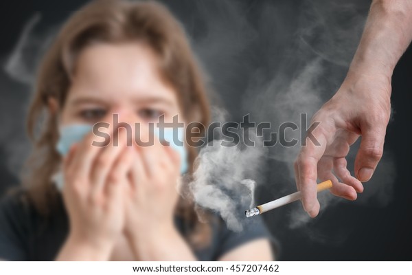 受動喫煙のコンセプト。女はたばこの煙で顔を覆っている。