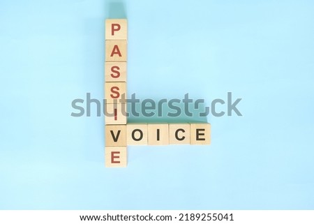 Passive voice topic in English grammar teaching. Wooden block crossword puzzle flat lay in blue background.