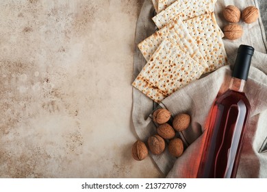 Passover celebration concept. Matzah, red kosher and walnut. Traditional ritual Jewish bread on sand color old concrete background. Passover food. Pesach Jewish holiday. 