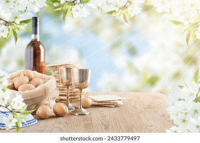 Passover celebration concept. Matzah, red kosher and walnut on wooden vintage table table in front of spring blossom tree garden and flowers landscape with sun rays with copy space. Mock up. - Powered by Shutterstock