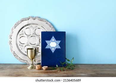 Passover Seder Plate With Torah And Cup On Table Against Color Background