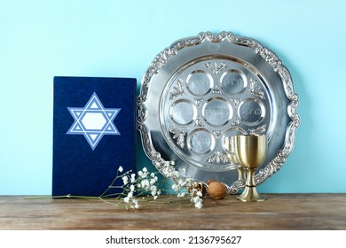 Passover Seder Plate With Torah And Cup On Table Against Color Background