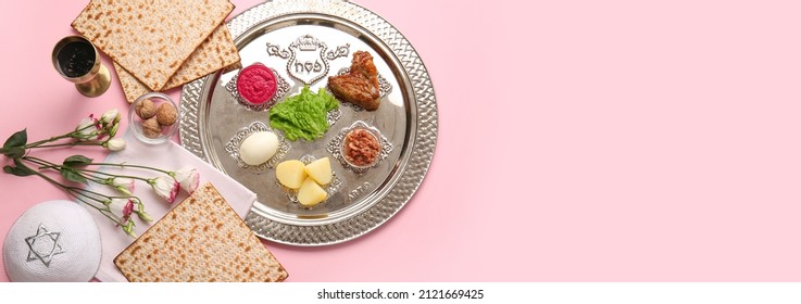 Passover Seder plate with traditional food and Jewish cap on pink background with space for text