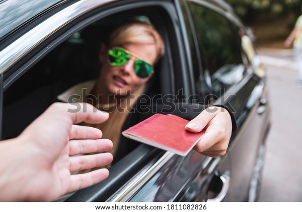 Passport in Female driver hand, close\
up. Woman VIP Giving pass for control. Attractive Driver with\
sunglasses holding ID Card in the Car on boarder\
Checkpoint