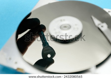 Password and data protection concept. A disassembled hard drive, pad lock and key in the hands of a hacker. Cyber security concept with a padlock on hard disk. Blocked storage device