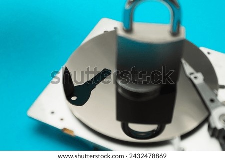 Password and data protection concept. A disassembled hard drive, pad lock and key in the hands of a hacker. Cyber security concept with a padlock on hard disk. Blocked storage device