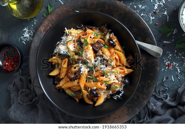 Pasta\
alla norma - Italian pasta with eggplant, tomato and parmesan\
cheese on dark table. Top view with copy\
space.
