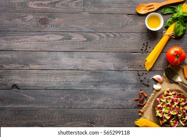 Pasta background. Several types of dry pasta with vegetables and herbs on a wooden table. Free space for text. Top view - Powered by Shutterstock