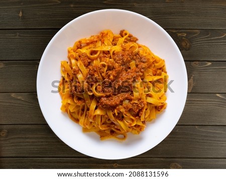 Pasta bolognese. Tagliatelle with bolognese sauce. Fettuccine with meat sauce. Tomato sauce and minced meat. Pasta with ragù, typical Italian food. Flat lay.