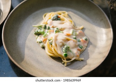 Pasta with broccoli, peas and carrots in alfredo sauce
