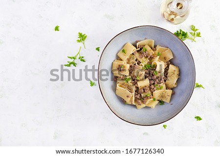 Pasta Calamarata with minced meat in blue bowl. Italian cuisine. Top view, overhead