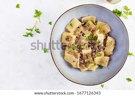 Pasta Calamarata with minced meat in blue bowl. Italian cuisine. Top view, overhead