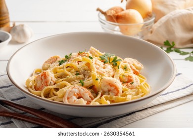 Pasta carbonara con camarones en plato blanco. Pasta fettuccine en salsa cremosa con gambas y cubierta con perejil y queso parmesano.