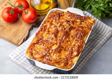 Pasta casserole bechamel sauce topped with melted mozzarella cheese and served in a white baking dish on a table (Turkish name; firinda makarna or firin makarna)