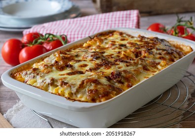 Pasta casserole with bolognese and bechamel sauce topped with melted mozzarella cheese and served in a white baking dish on a table