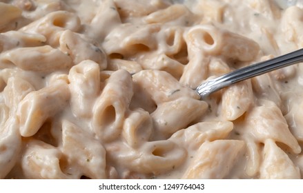 Pasta With Chicken In An Alfredo Sauce With A Spoon In The Food While Cooking In A Pan.