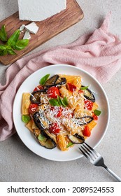 Pasta With Eggplant, Tomato Sauce, Basil, Served With Grated Ricotta Salata Cheese. Pasta Alla Norma, Pasta Salad. Pink And Beige Table Surface. Directly Above, Vertical Image.