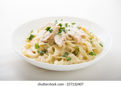 Pasta fettuccine alfredo with chicken, parmesan and parsley on white background close up. Italian cuisine. - Powered by Shutterstock