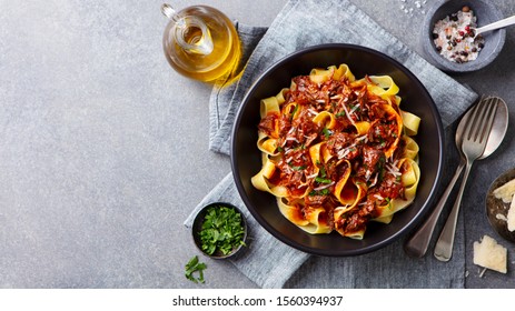 Pasta fettuccine with beef ragout sauce in black bowl. Grey background. Copy space. Top view. - Shutterstock ID 1560394937