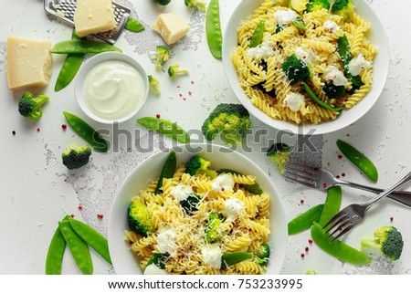 Pasta with green vegetables broccoli, Mange tout and creamy sauce in white plate.