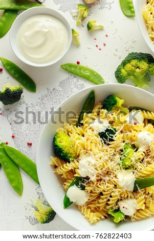 Pasta with green vegetables broccoli, Mange tout and creamy sauce in white plate
