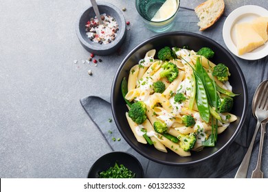 Pasta with green vegetables and creamy sauce in black bowl on grey stone background. Top view. Copy space. - Shutterstock ID 601323332