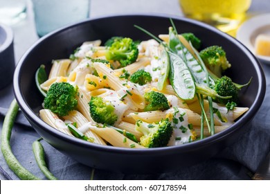 Pasta with green vegetables and creamy sauce in black bowl on grey stone background. - Powered by Shutterstock