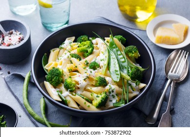 Pasta with green vegetables and creamy sauce in black bowl on grey stone background. - Powered by Shutterstock