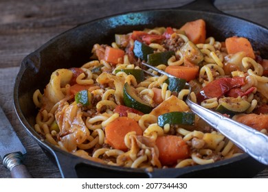 Pasta With Ground Beef, Cabbage And Vegetables Served With Fork In Pan On Wooden Table.