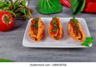 Pasta jumbo shells stuffed with minced beef meat and tomato sauce on a plate.