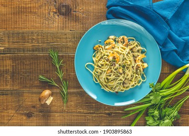 Pasta Linguine With Mushrooms, Shrimps And Seafood Mussels, Cheese And Herbs, In Blue Ceramic Plate On A Dark Wooden Table Surface.