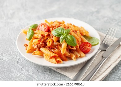 Pasta Penne Bolognese in white plate on light background. Bolognese sauce is classic italian cuisine dish. Popular italian food.
