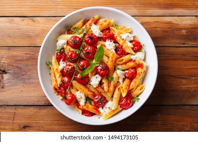 Pasta penne with roasted tomato, sauce, mozzarella cheese. Wooden background. Top view. - Powered by Shutterstock