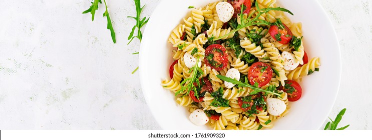 Pasta salad. Fusilli Pasta - Caprese salad with tomato, mozzarella and basil. Top view, banner, copy space - Powered by Shutterstock