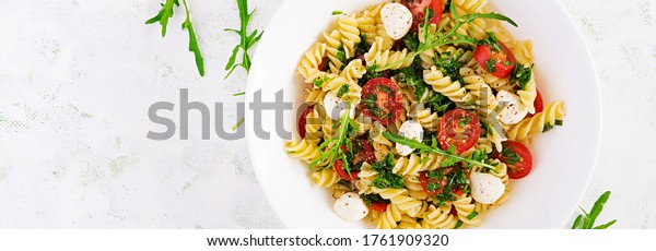 Pasta salad. Fusilli\
Pasta - Caprese salad with tomato, mozzarella and basil. Top view,\
banner, copy space