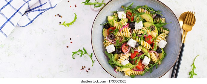 Pasta Salad With Tomato, Avocado, Black Olives, Red Onions And Cheese Feta. Mediterranean Cuisine. Top View, Overhead, Banner