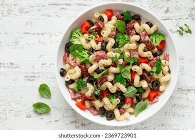 pasta salad  with vegetables, black olives, sun dried tomatoes and salami in white bowl, top view - Powered by Shutterstock