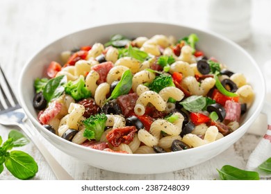 pasta salad  with vegetables, black olives, sun dried tomatoes and salami in white bowl - Powered by Shutterstock