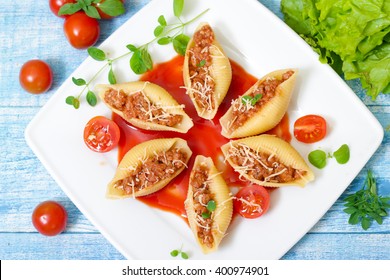 pasta shells stuffed with minced beef meat with herbs and tomato sauce on a plate 