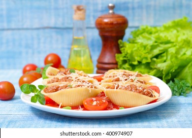 pasta shells stuffed with minced beef meat with herbs and tomato sauce on a plate 