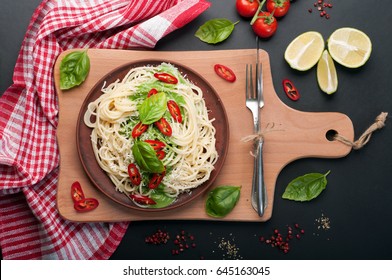 Pasta (spaghetti) with basil and cream sauce, grated cheese and pieces of hot pepper on a clay brown plate on a dark surface. Italian food. Vegetarian concept. Delicious and healthy lunch - Shutterstock ID 645163045