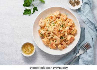 Pasta spaghetti with grilled shrimps bechamel sauce. Spaghetti with seafood rich cream. Cooking mediterranean food with savory prawns, copy space top view, blue table, italian cuisine